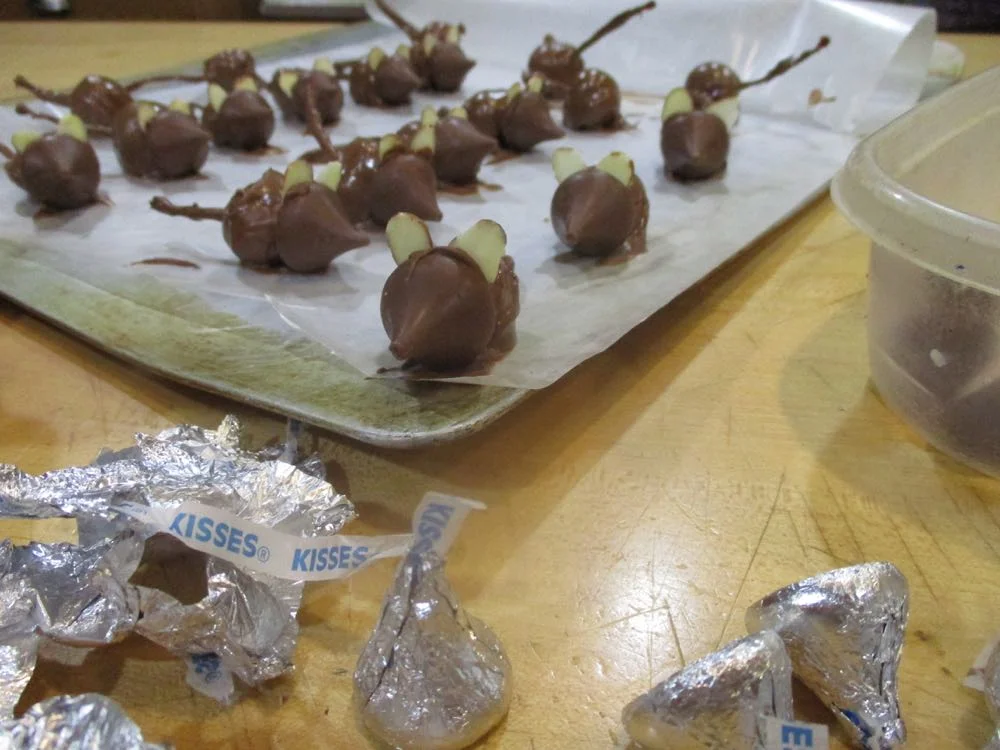 Hershey kisses form the face of chocolate-dipped maraschino cherries with stems.