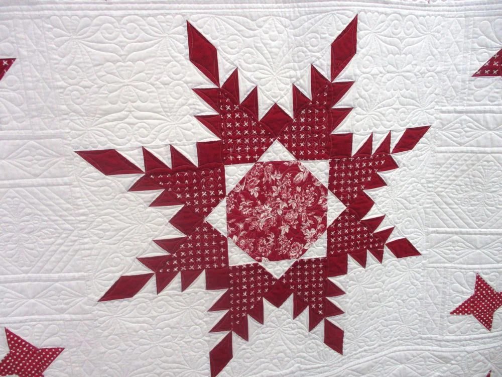 Center block of this red and white handmade quilt raffled by Piece and Plenty Quilt Guild.