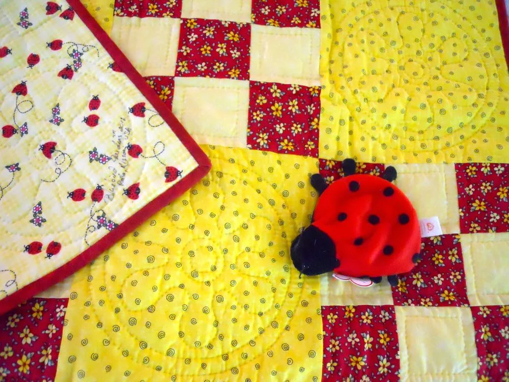 A ladybug toy was added to this ninepatch ladybug baby quilt. (Photo by Charlotte Ekker Wiggins)