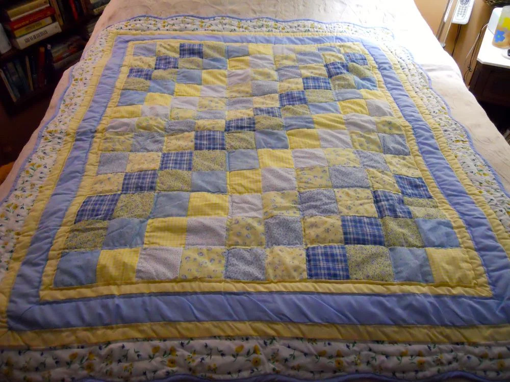 Blue Yellow Ninepatch Lap Quilt Wall Hanging on a bed to show all of the included fabric colors.