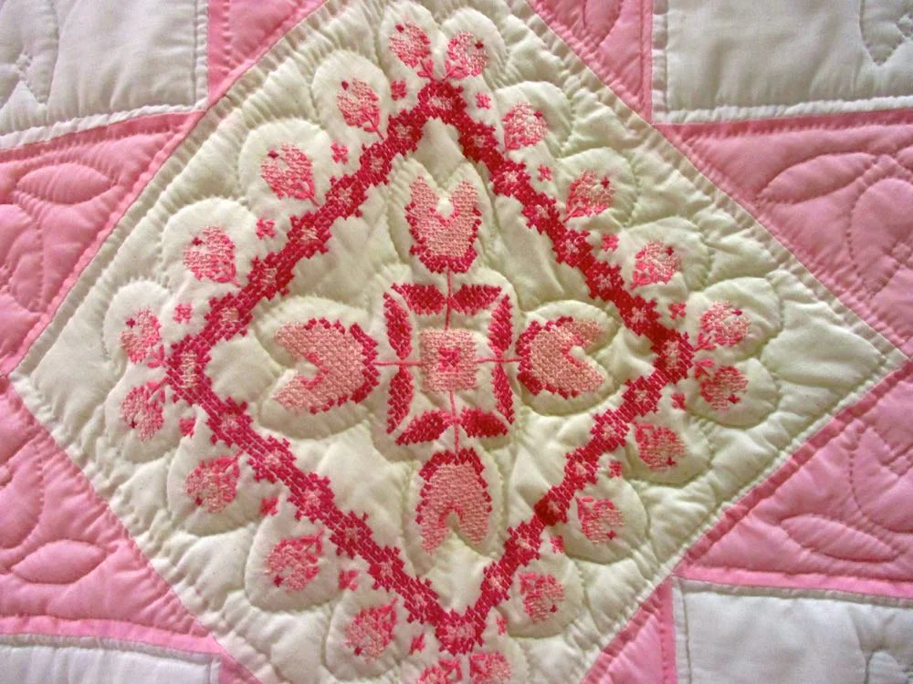 Very detailed embroidery makes up Pink Cross Stitch Quilt blocks. (Photo by Charlotte Ekker Wiggins)