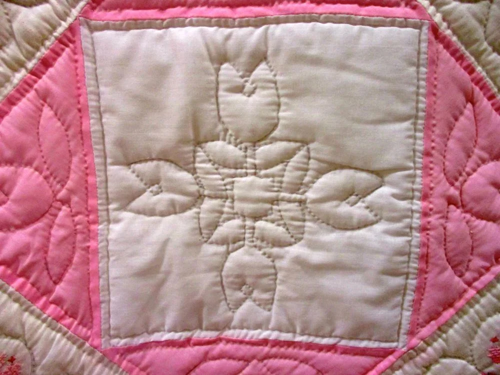 Hand quilting repeats the pink cross stitch quilt design. (Photo by Charlotte Ekker Wiggins)