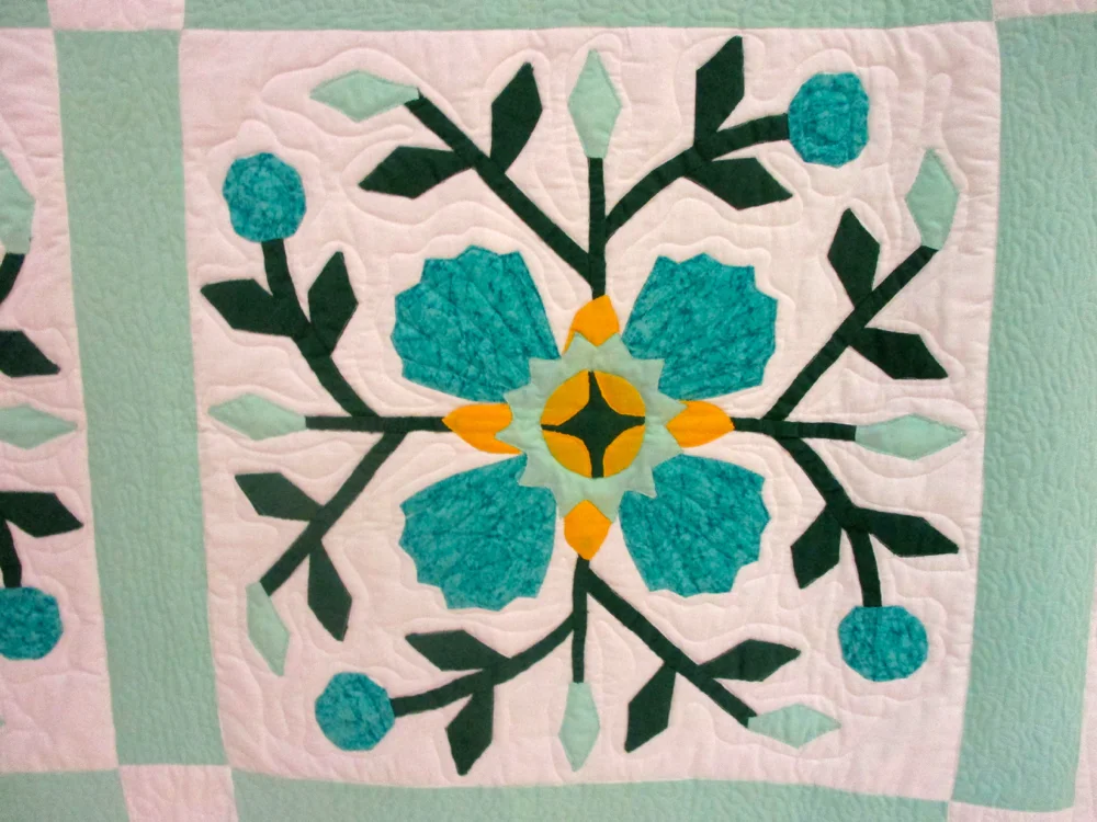 Unusual colors for a rose quilt, aquamarine fabrics against white. (Photo by Charlotte Ekker Wiggins)