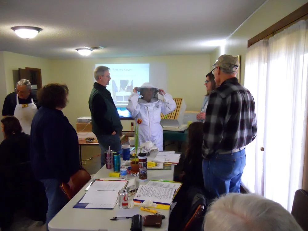 Beginning beekeeping class students get to try on beekeeping suits to get the right size.