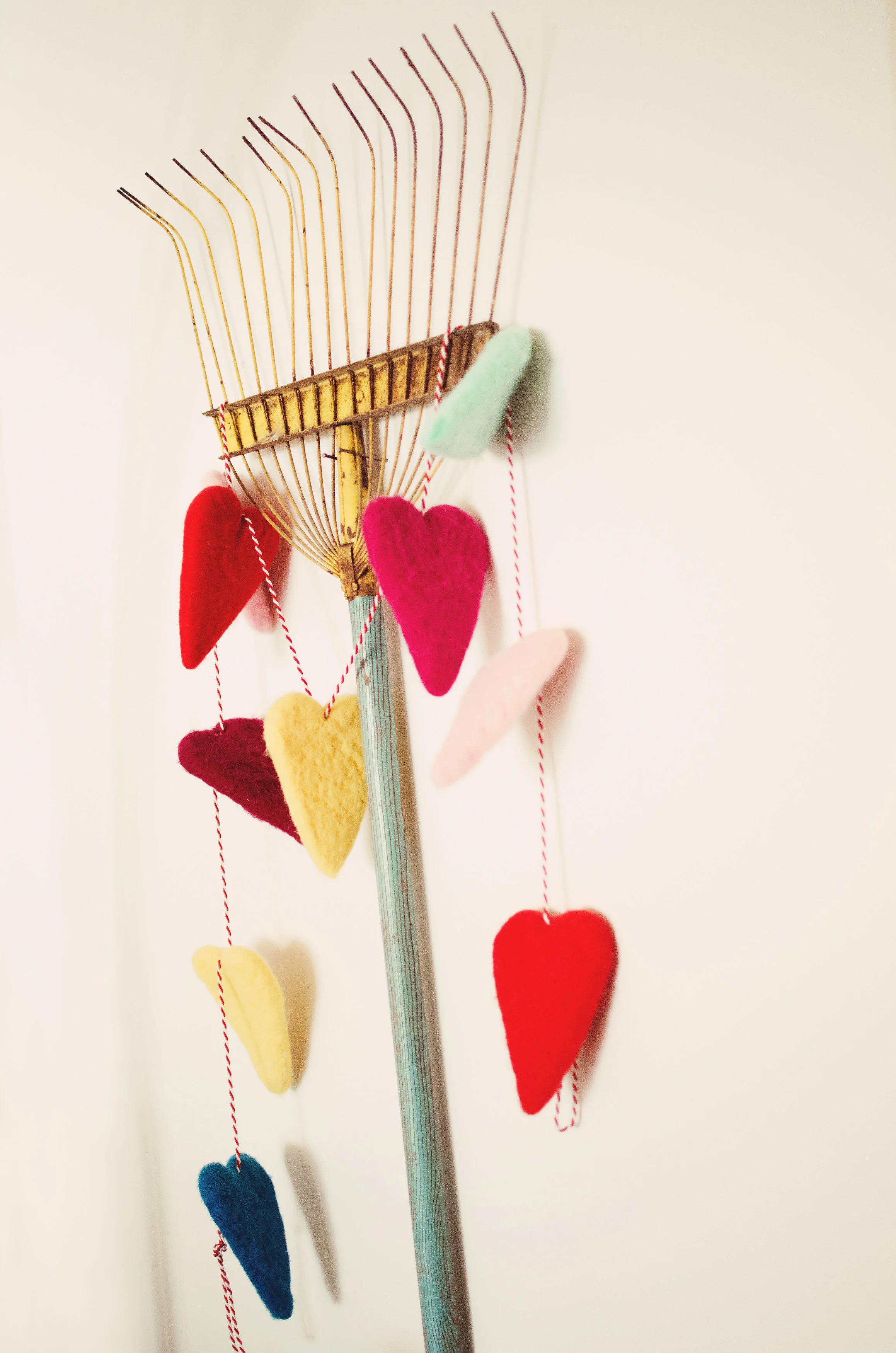 Vintage rake used as wall decor with heart garland. H.Prall & Co. | hprallandco.com
