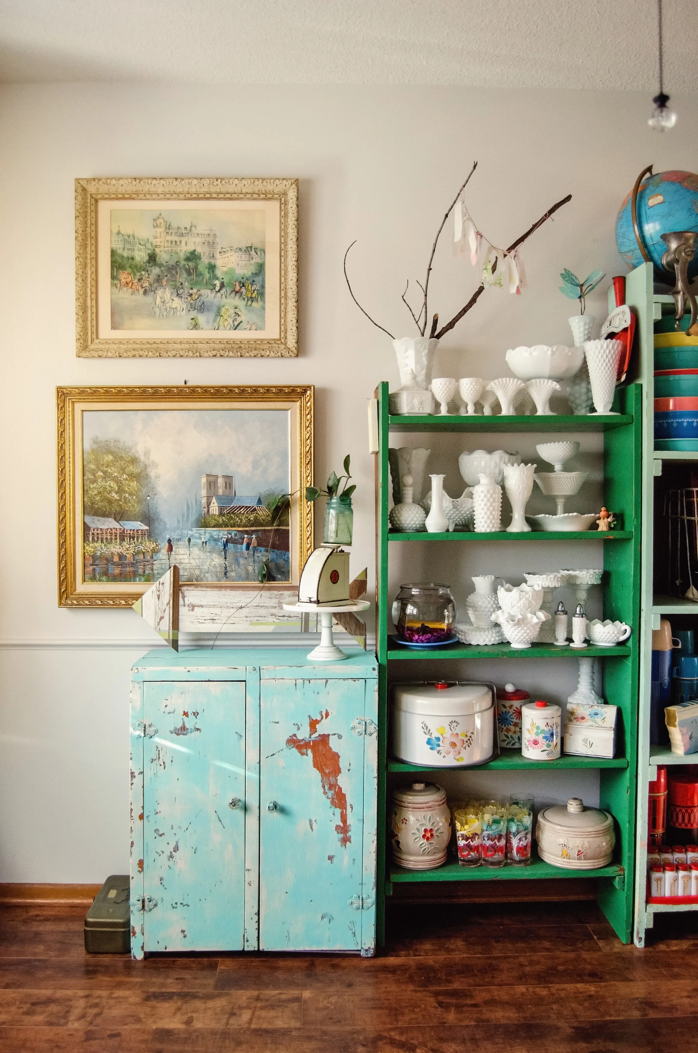 A chippy aqua cabinet next to kelly green shelving holding vintage milk glass. H.Prall & Co. | hprallandco.com