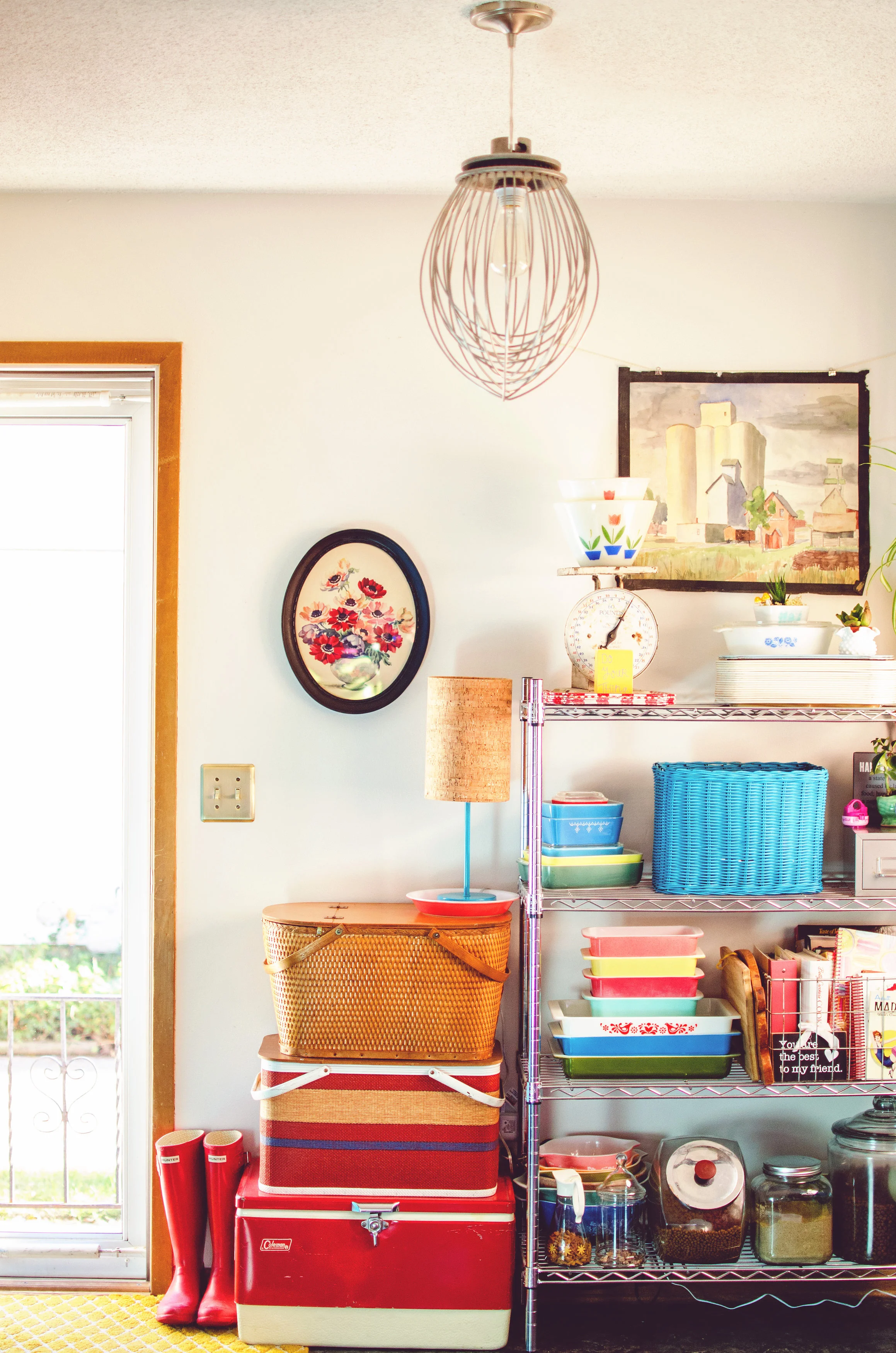 Metal wisk light fixture above a metal shelf with vintage baskets, and Pyrex dishes. H.Prall & Co. | hprallandco.com