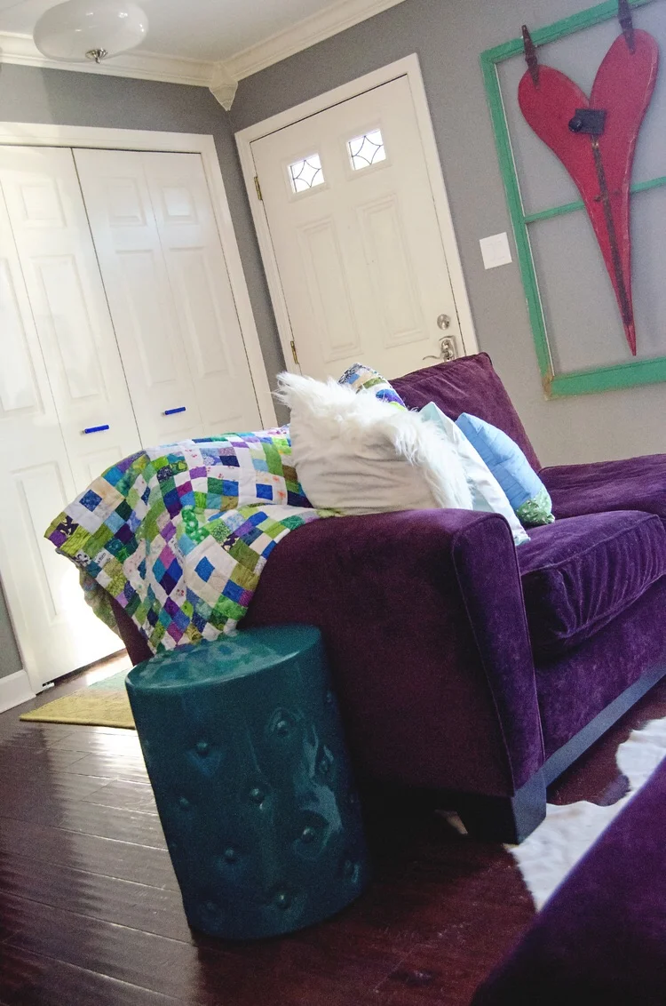 Purple loveseat with a bright quilt and teal garden stool as an endtable. || RustopiaConsulting.com