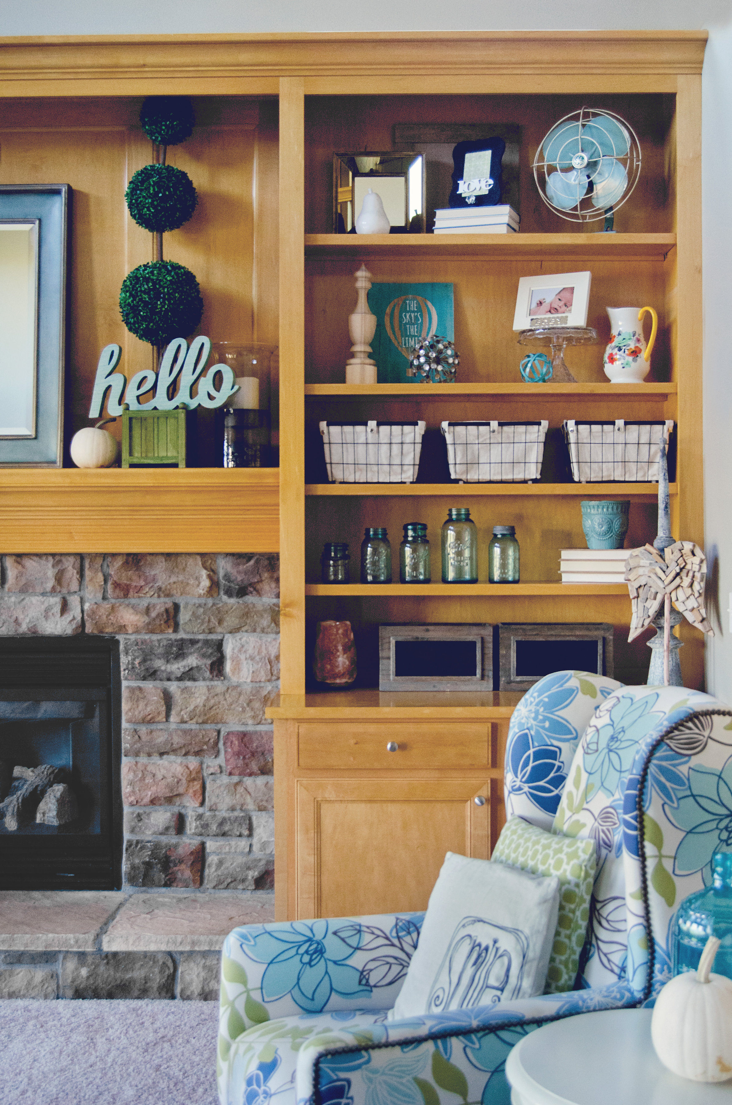 Built-in bookshelf styled in a living room with pops of blue and green. | hprallandco.com