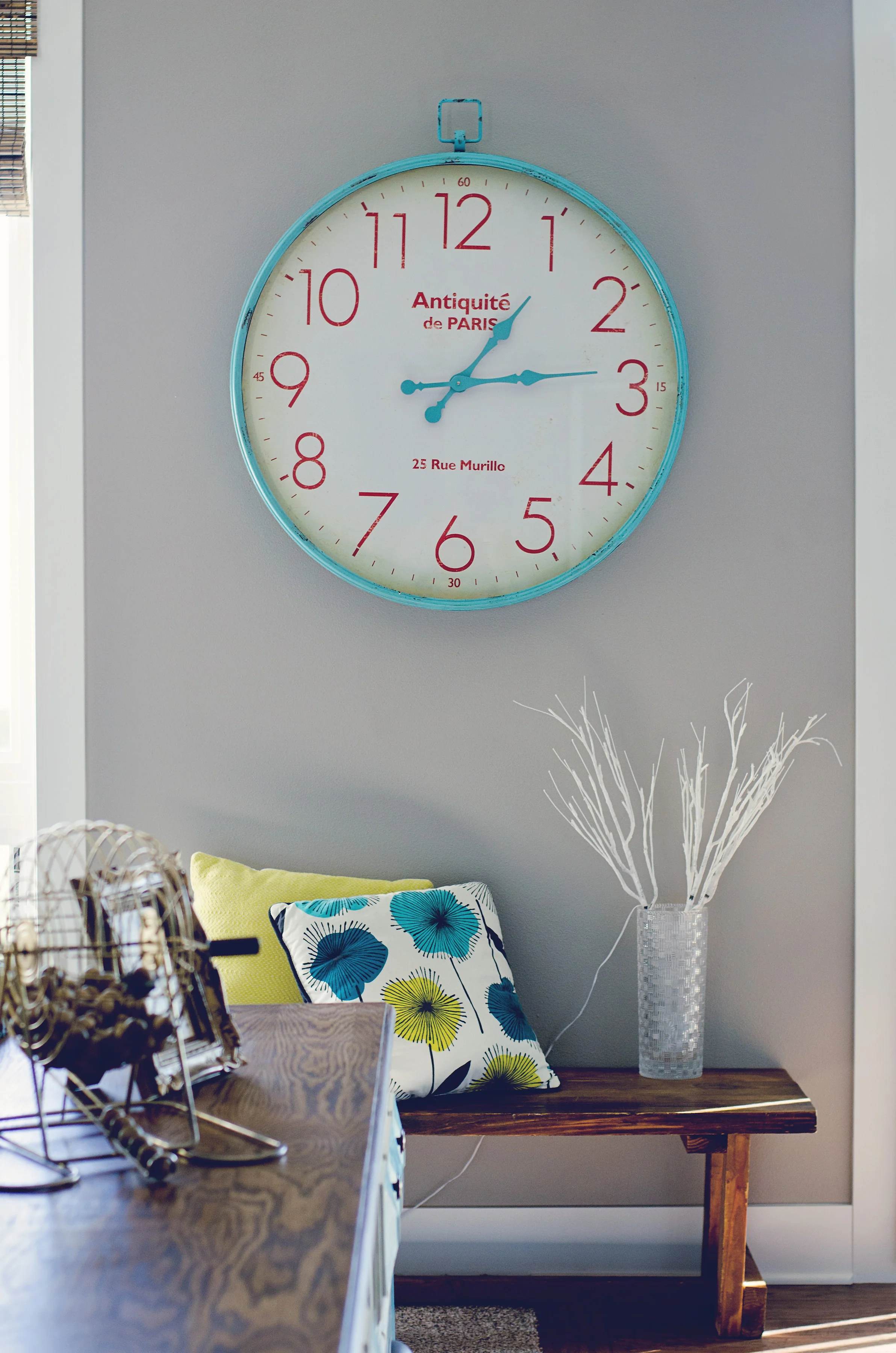 Aqua and red wall clock over a sweet wooden bench. || RustopiaConsulting.com