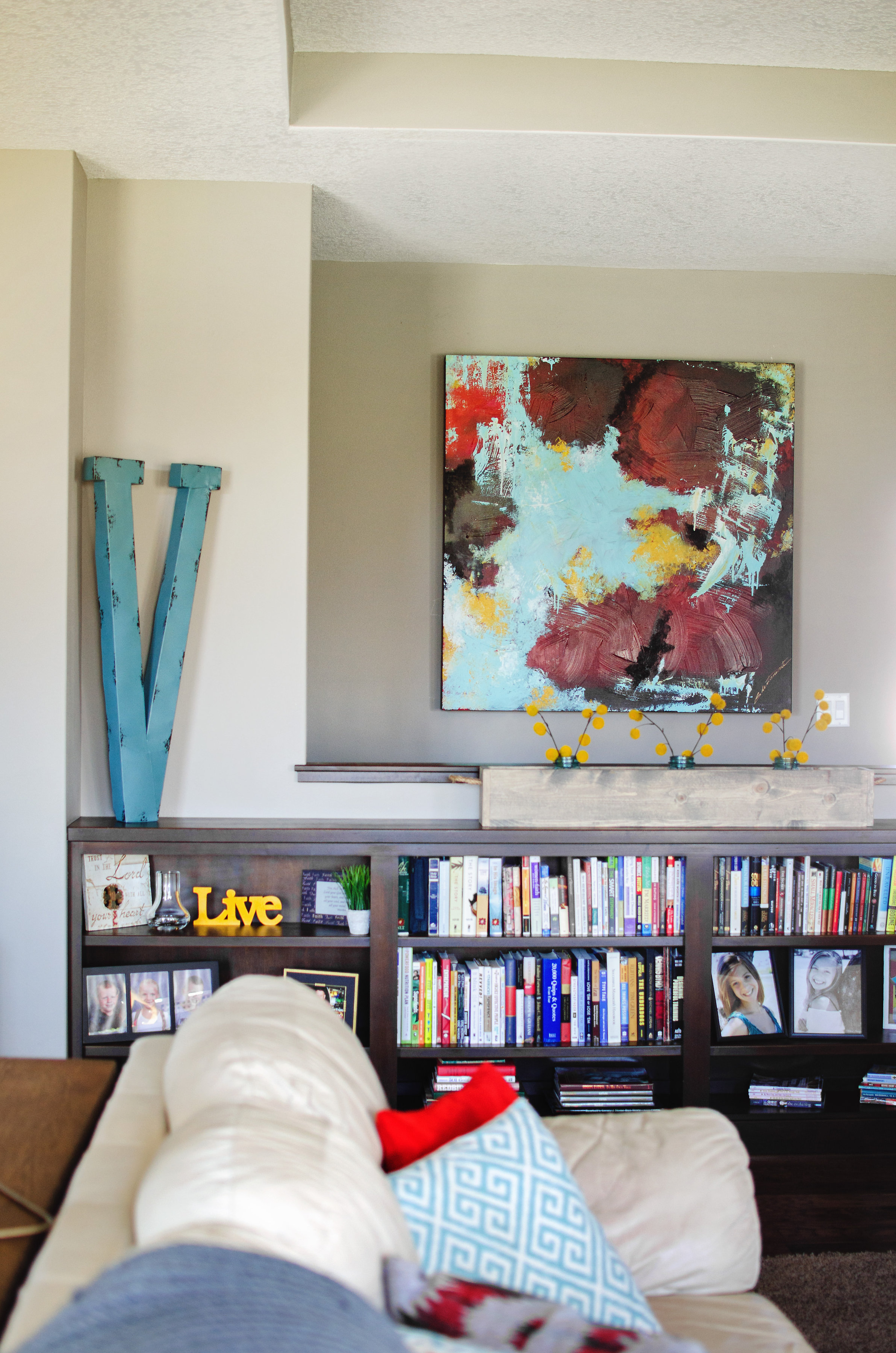 Abstract painting and over-sized monogram over a bookshelf. | hprallandco.com