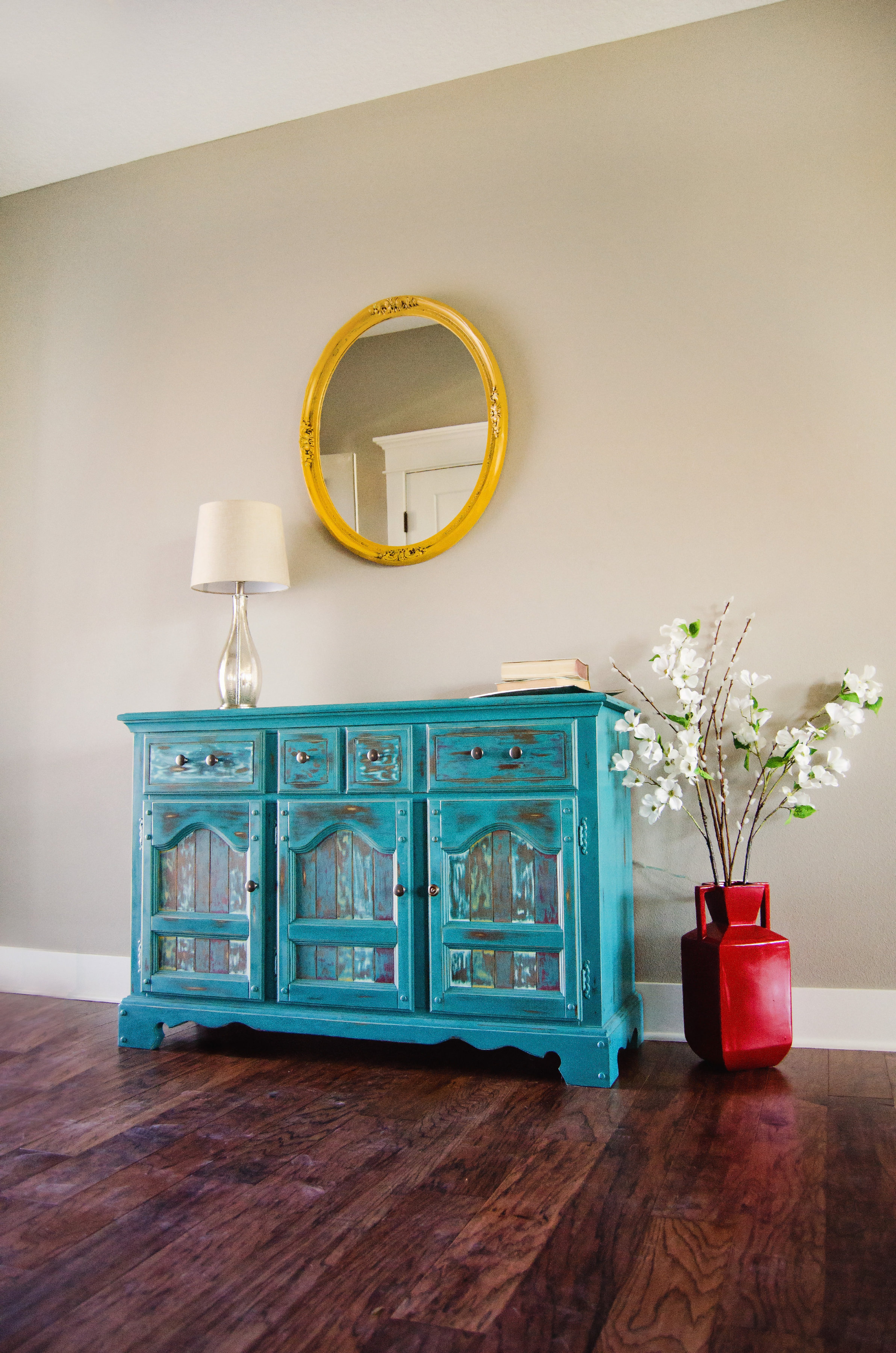 Aqua cabinet with a yellow round mirror hanging above it. H.Prall & Co. | hprallandco.com