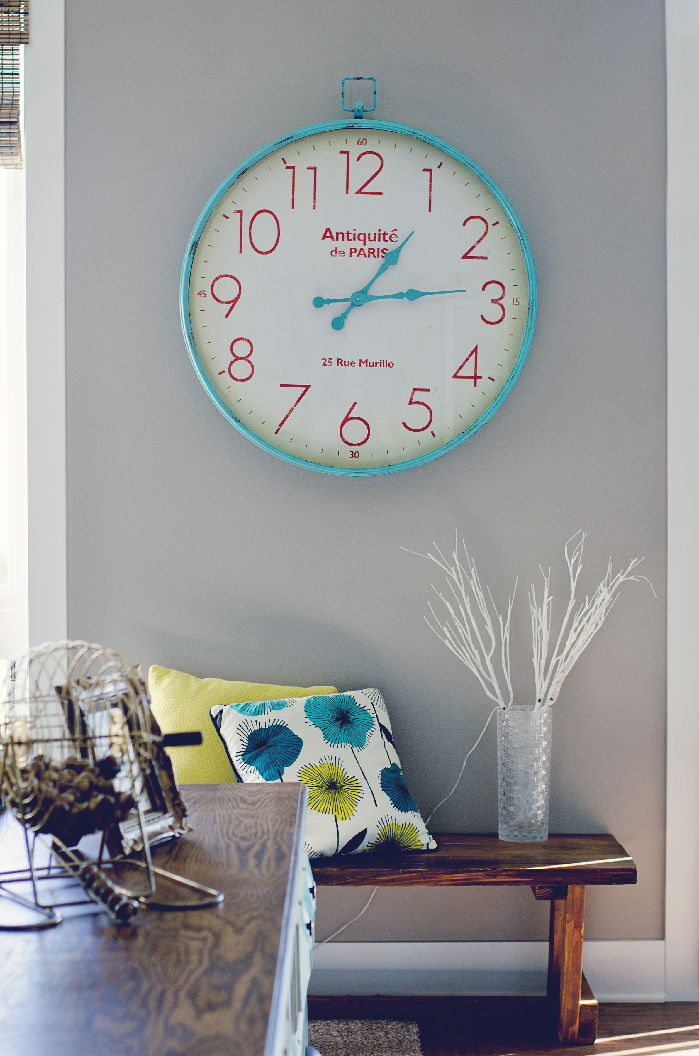 Turquoise and red wall clock over a bench. | hprallandco.com