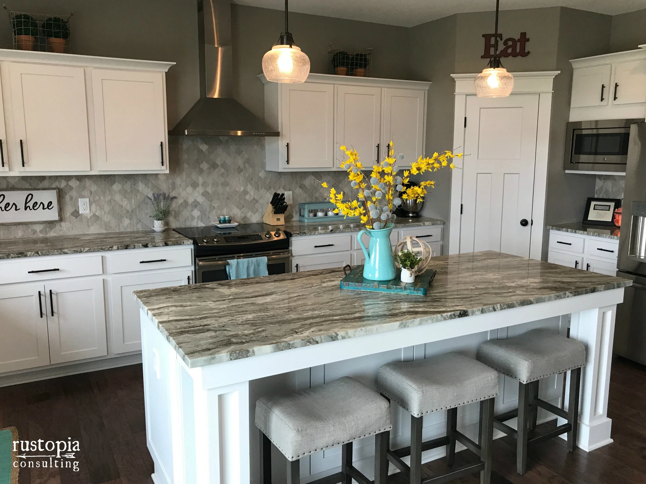 Kitchen with white cabinets, granite counters, and a colorful vignette on the kitchen island. | RustopiaConsulting.com