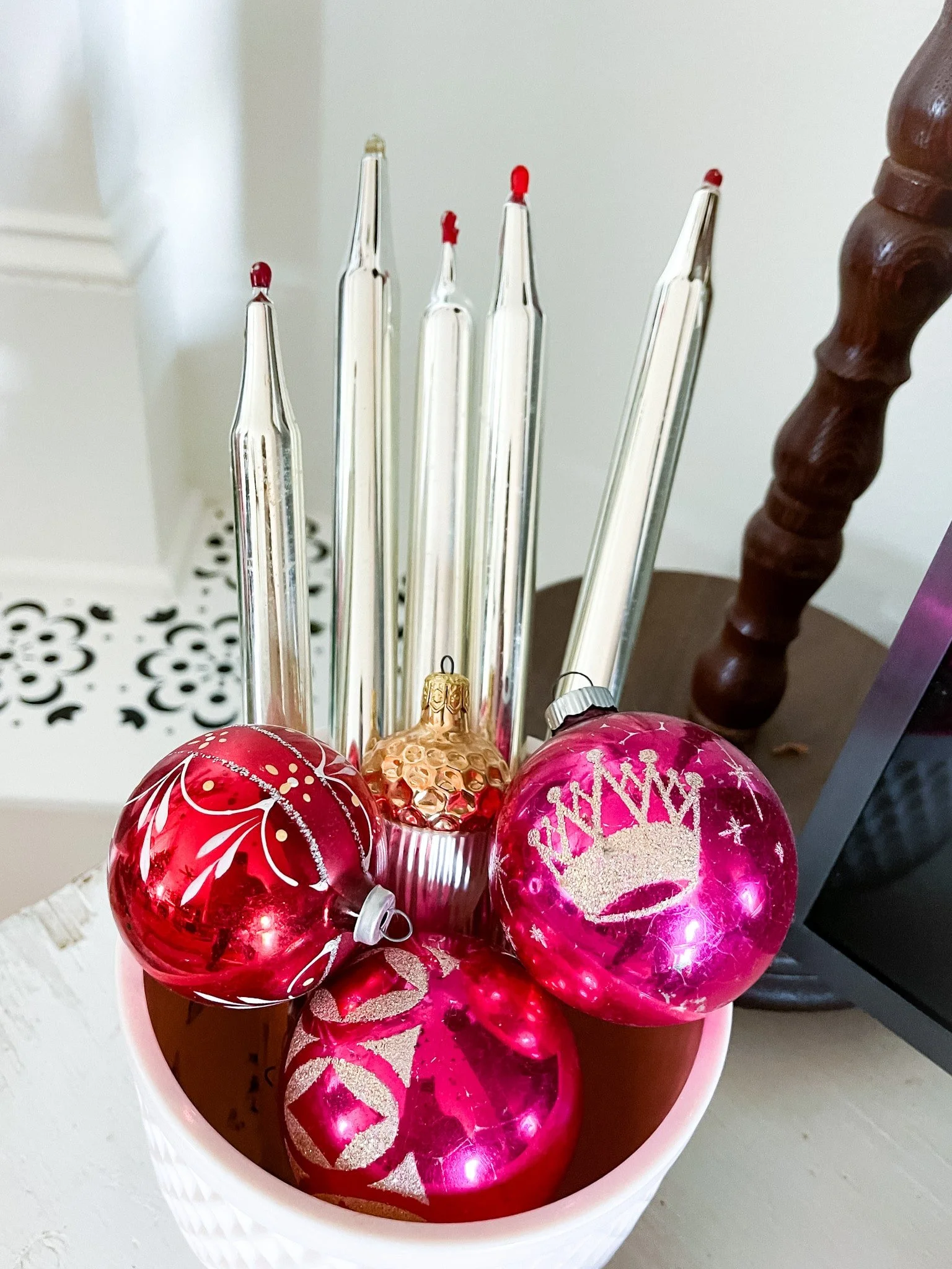 Vintage mercury glass and Shiny Brite ornaments in a pink milk glass planter. Also seen are mercury glass taper candles.