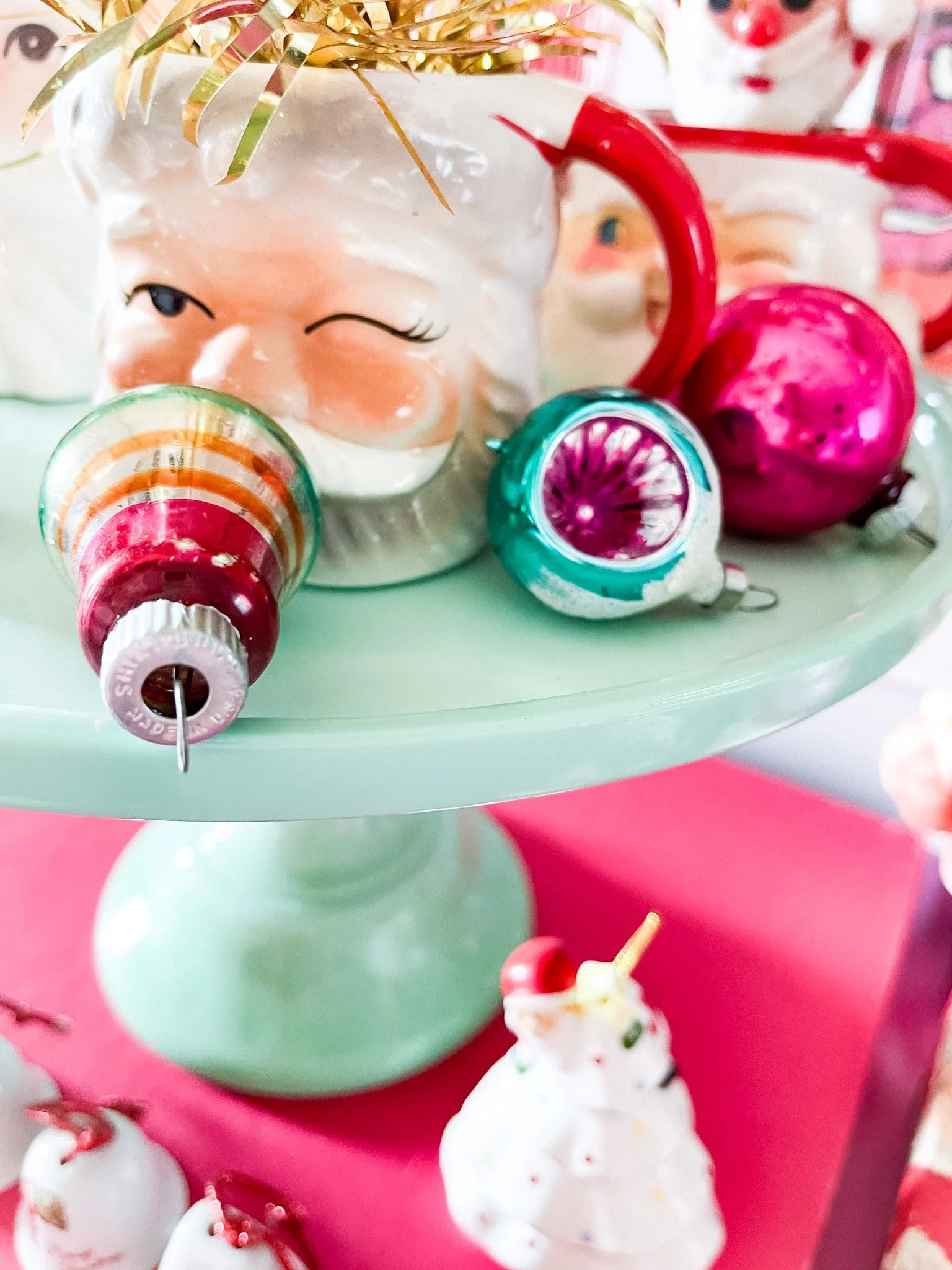 Vintage mercury glass and Shiny Brite ornaments on jadeite cake stand. Vintage santa mugs and decorations.