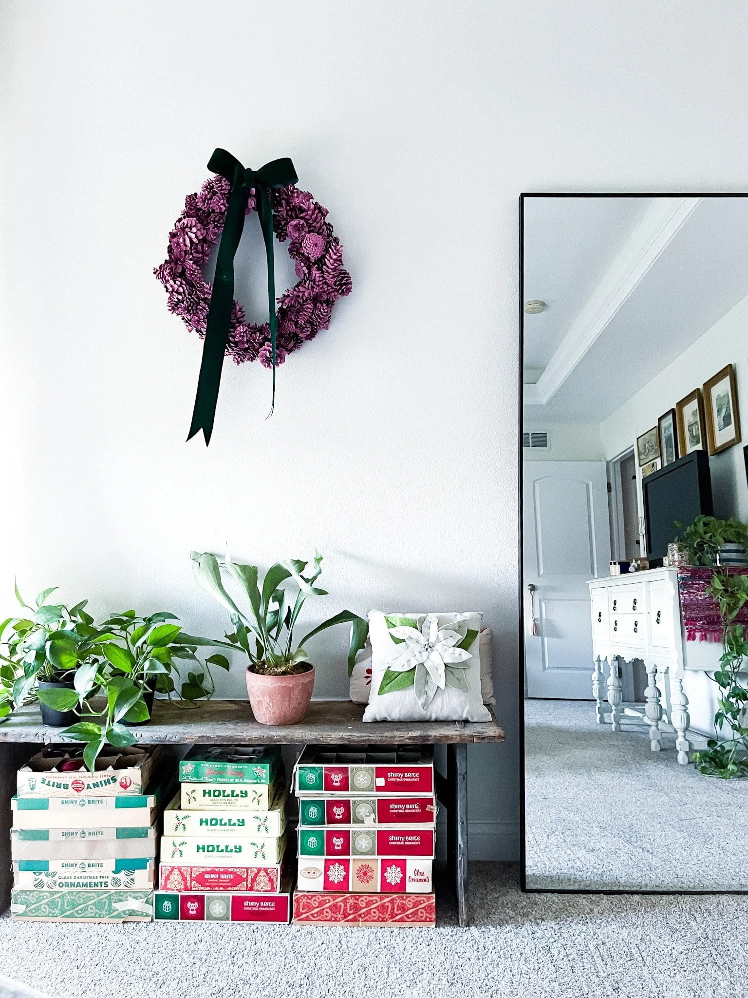 Vintage Christmas ornament cardboard boxes under a primitive bench with plants on it.
