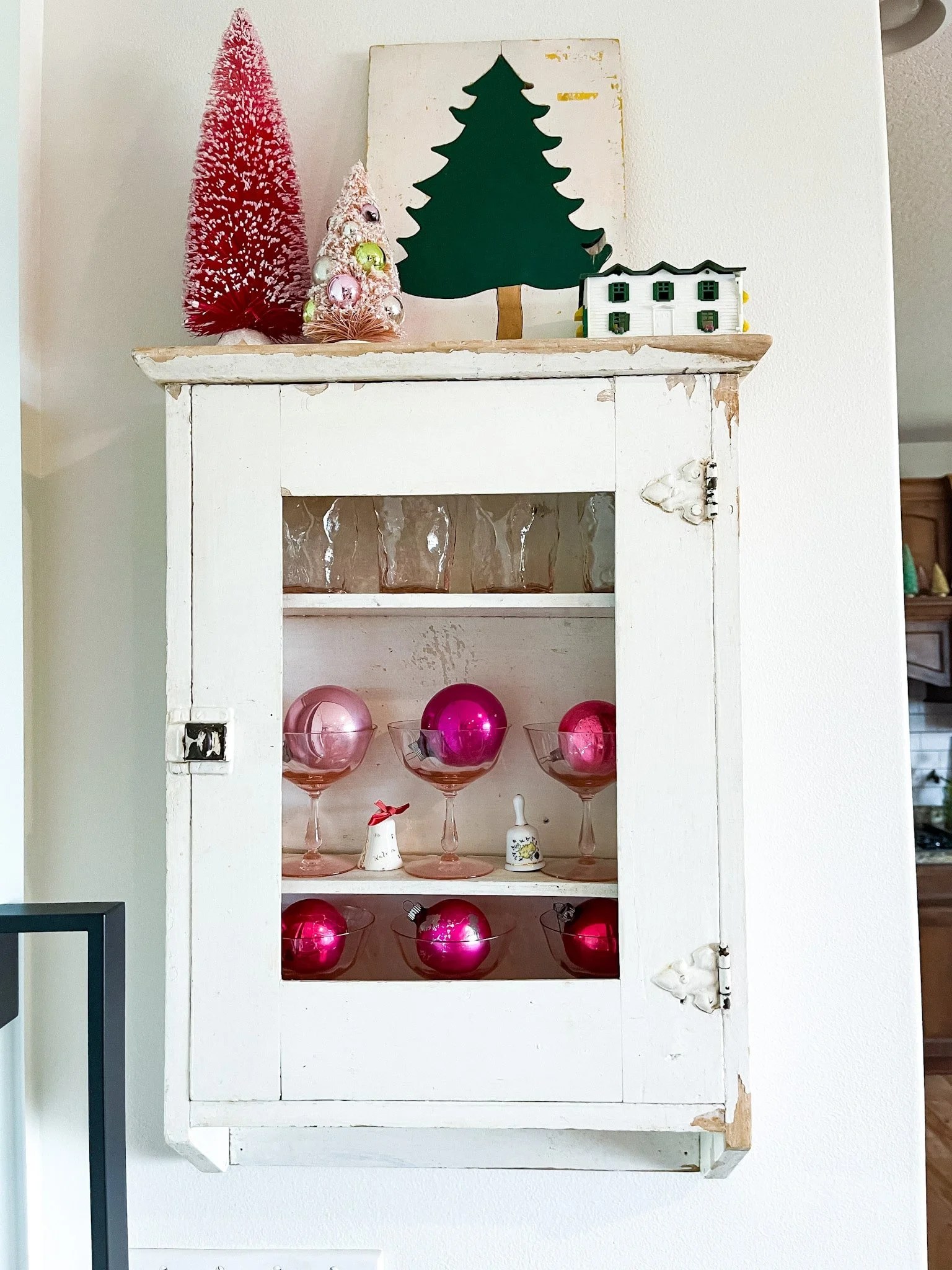 Vintage mercury glass and Shiny Brite ornaments in colored glassware. Antique farmhouse medicine cabinet. Bottle brush trees.