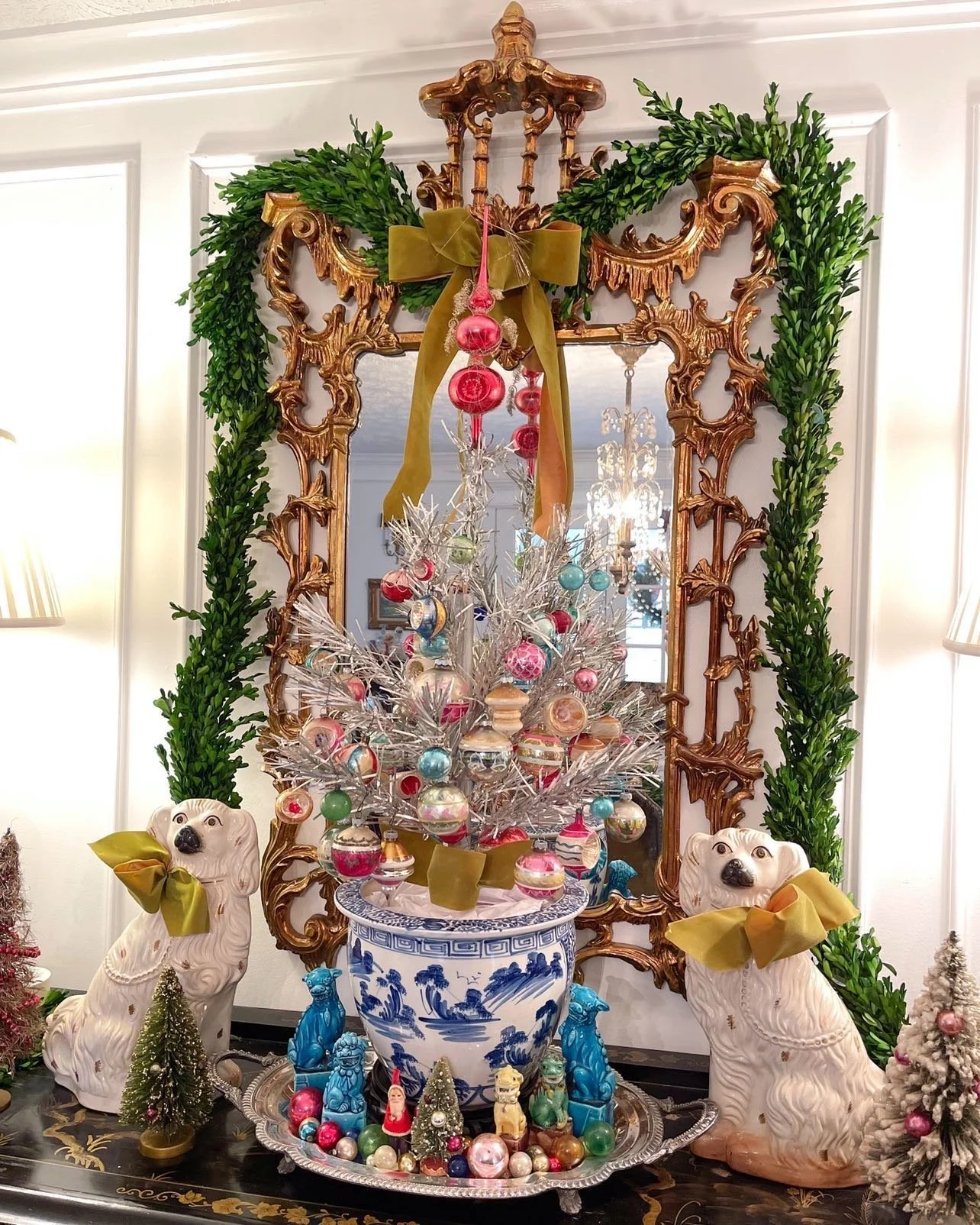 Vintage Shiny Brite ornaments on a tinsel tree in entryway. Chinoiserie style vignette. Staffordshire dog figurines.