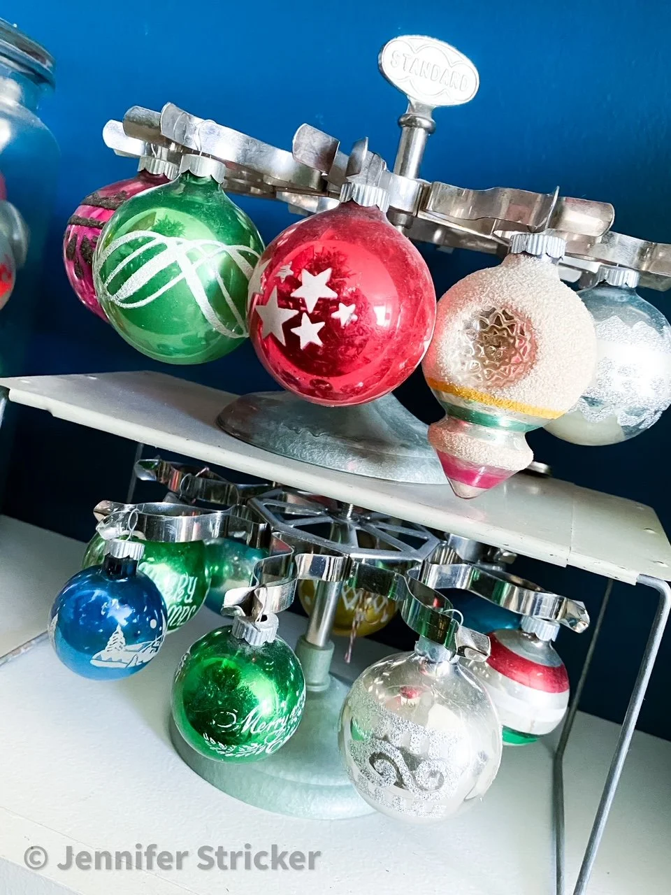 Vintage Shiny Brite Christmas ornaments displayed on a metal stamp holder.
