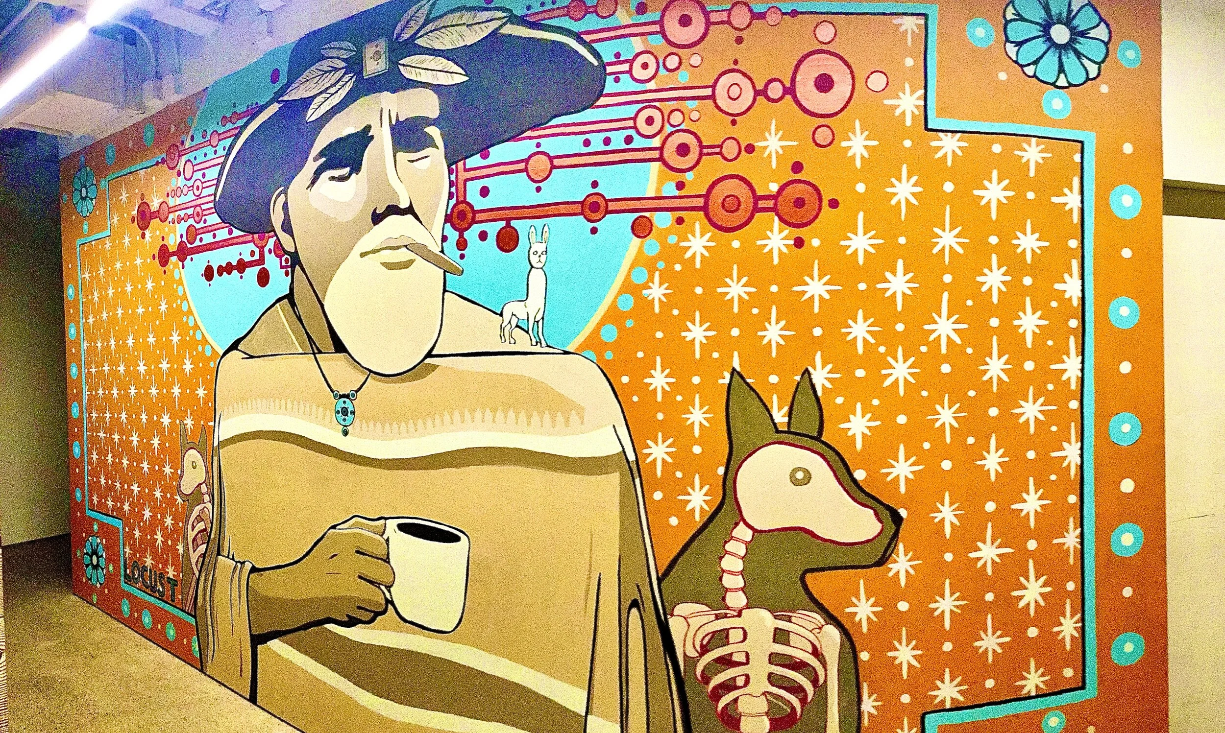 Colorful mural featuring a cartoon man with a mustache, wearing a hat with feathers, holding a cup, with a small dog on his shoulder and a skeleton with a dog's head next to him. The background includes orange and blue patterns, flowers, and star sha