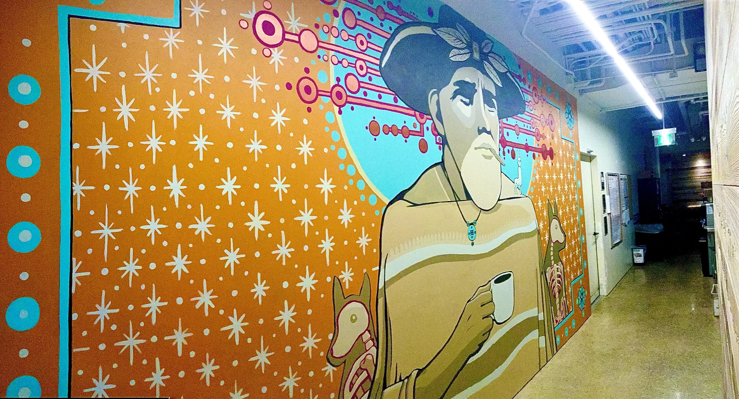 Colorful mural depicting a man with traditional Asian features, wearing a hat and holding a coffee cup, with whimsical animal and floral designs in the background.