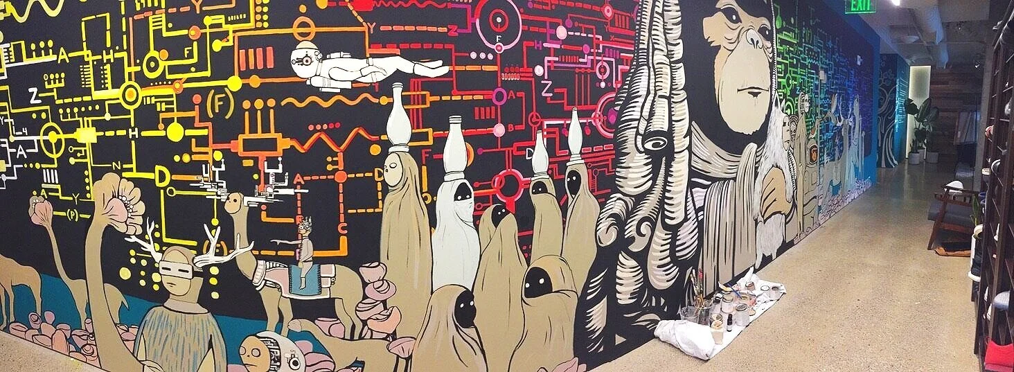 Colorful mural featuring abstract and stylized characters including a large white gorilla and ghost-like figures with black eyes, all set against a vibrant background with circuit-like patterns in yellow, red, and pink.