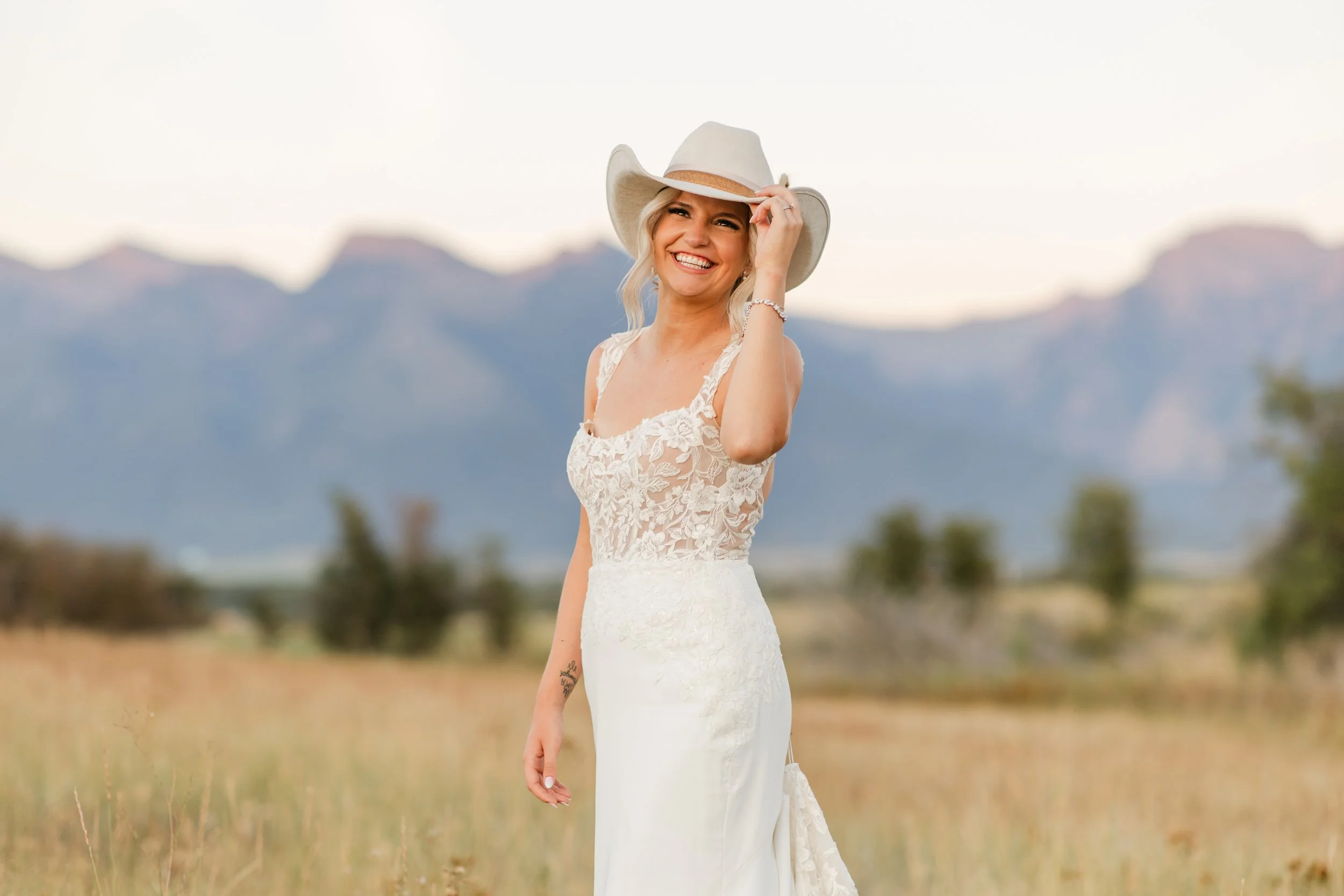 Bride tips her cowboy hat in front of the Mission Mountains at the Rugged Horizon wedding venue in St. Ignatius, Montana.
