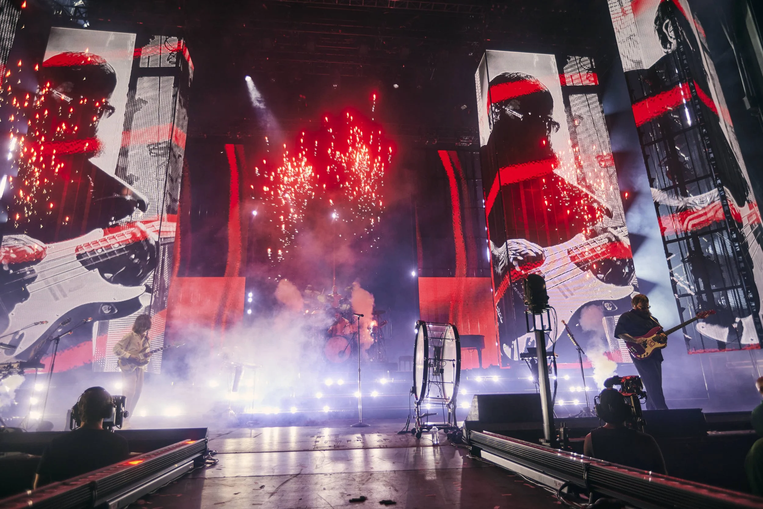 Imagine Dragons Stage Design with large LED screens displaying a musician playing guitar, colorful lights, and smoke effects. Mitchell Schellenger Designer