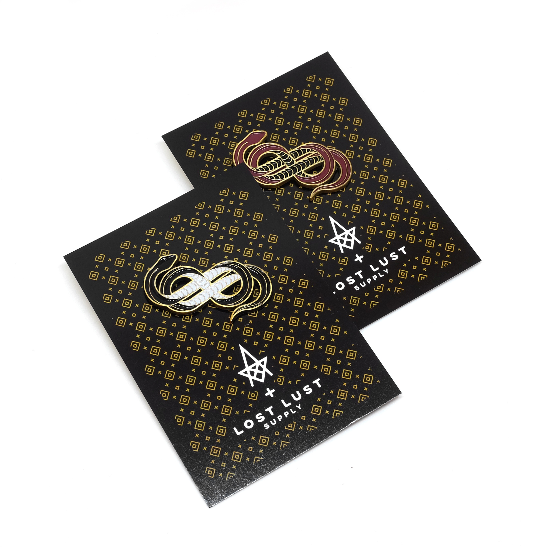 Custom black and oxblood red snake die-cast enamel pins with backing cards, designed by Adam Vass of La Dispute, for Lost Lust Supply.
