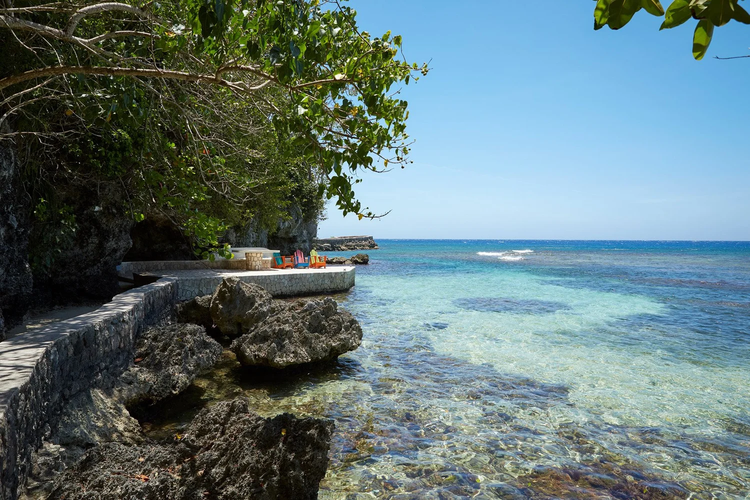 Paseo de piedra junto a una costa rocosa y aguas transparentes.