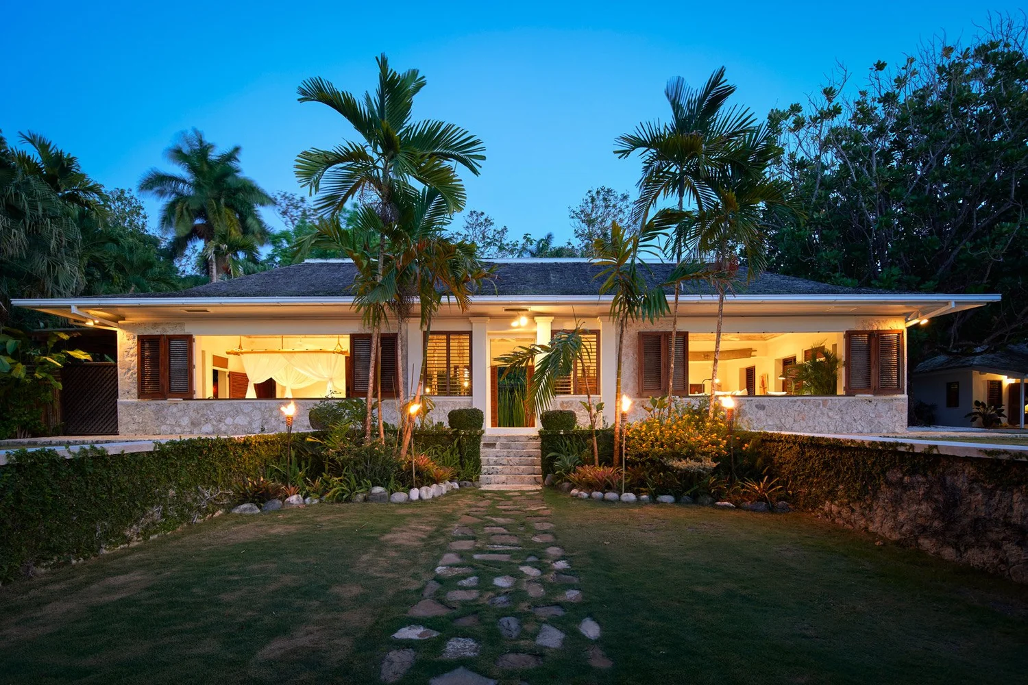 Villa iluminada entre palmeras al anochecer, en la serie de Jamaica para Airbnb Luxe.