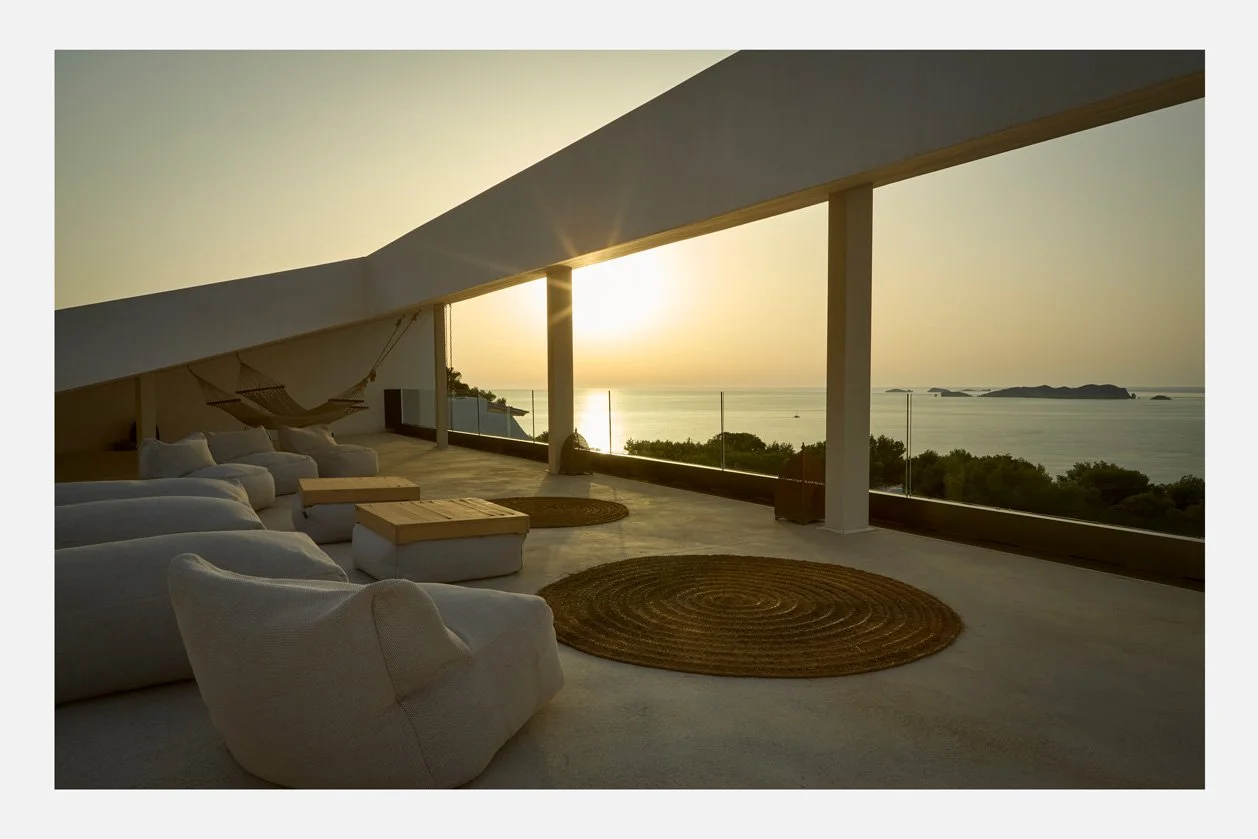 Terraza superior de Cala Moli con asientos blancos frente al atardecer