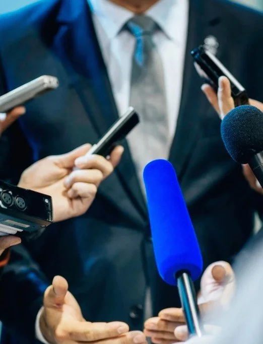 An executive being interviewed by multiple journalists