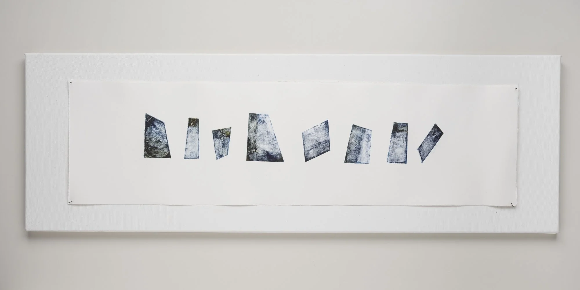 Abstract artwork featuring a series of irregularly shaped, textured blue and black blocks arranged in a horizontal line on a white background, framed with a white border.