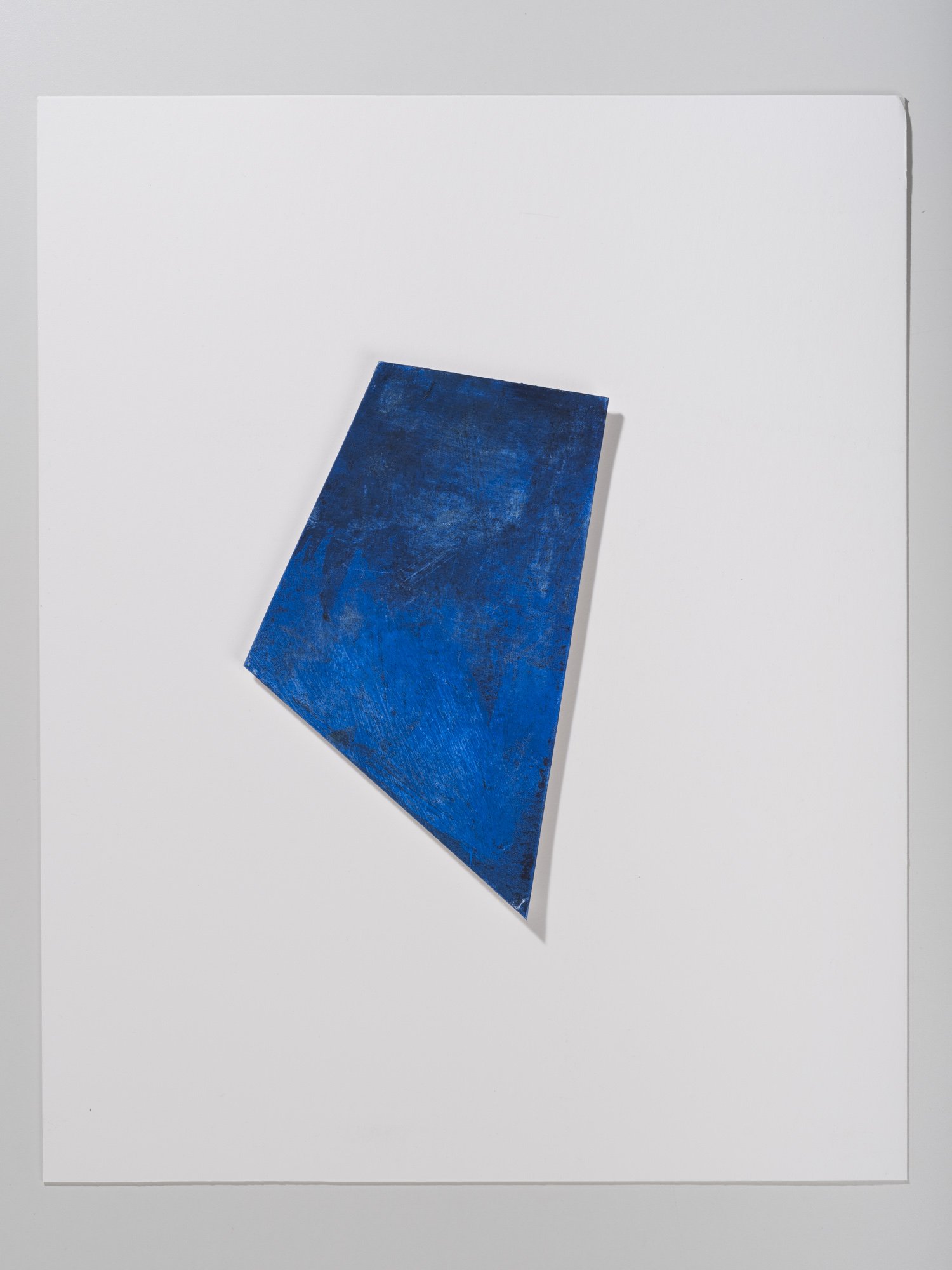 A blue rectangular object, likely a piece of paper or card, placed on a white background with a slight shadow visible on the right side.