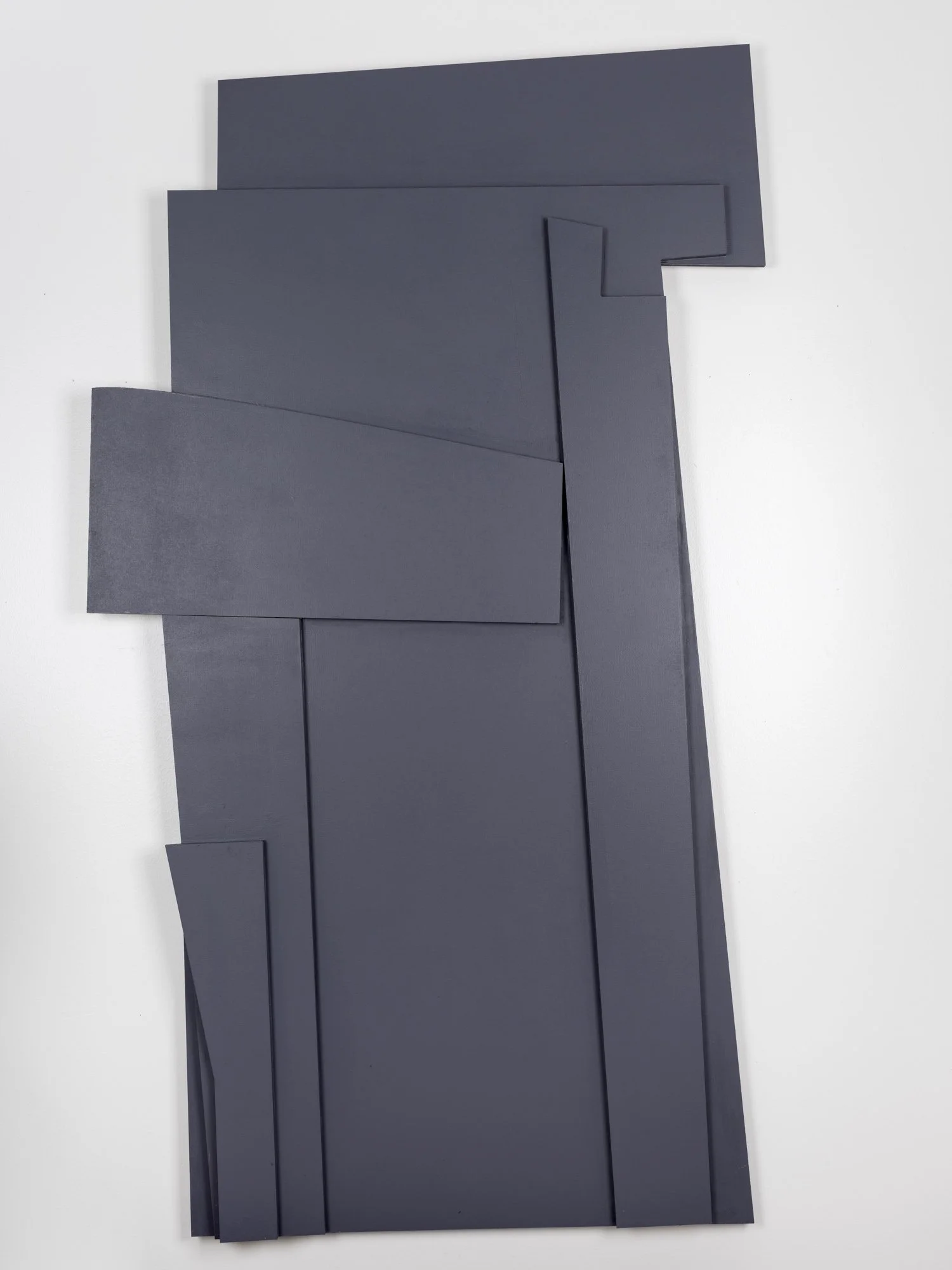 Multiple dark gray rectangular foam boards with cut-out sections, arranged on a white surface.