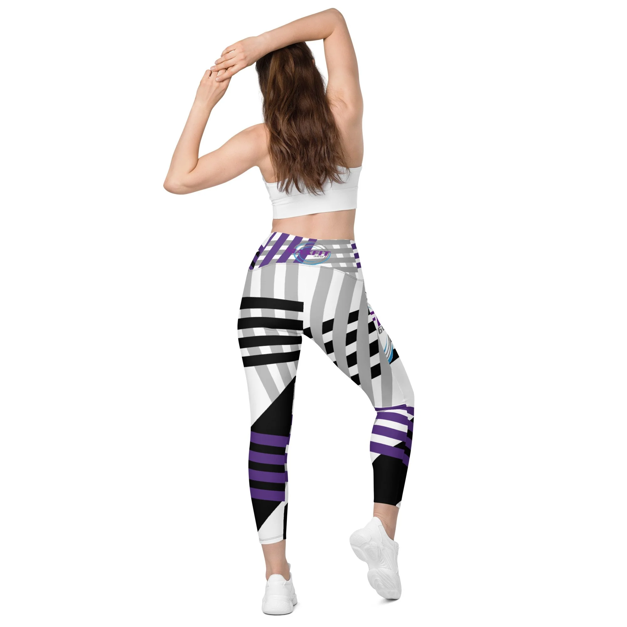 Rear view of model in active posture, arms over head.  displaying MAXFIT 360 Leggings with pockets.  The leggings are white with bold patterns of stripes in black, grey and purple.