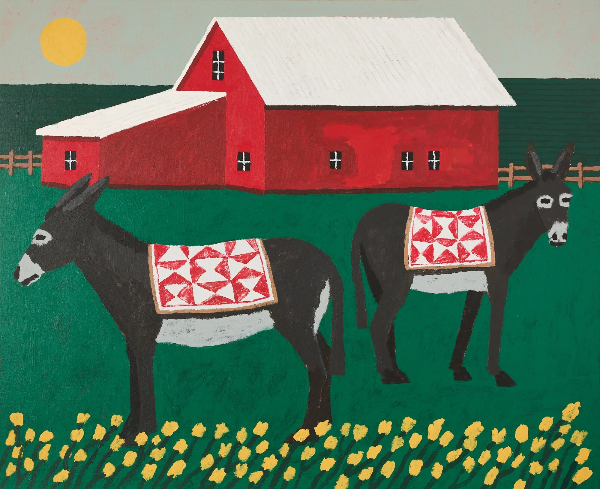 two donkeys standing in a green field in front of a red barn with hills and a sunset in the background