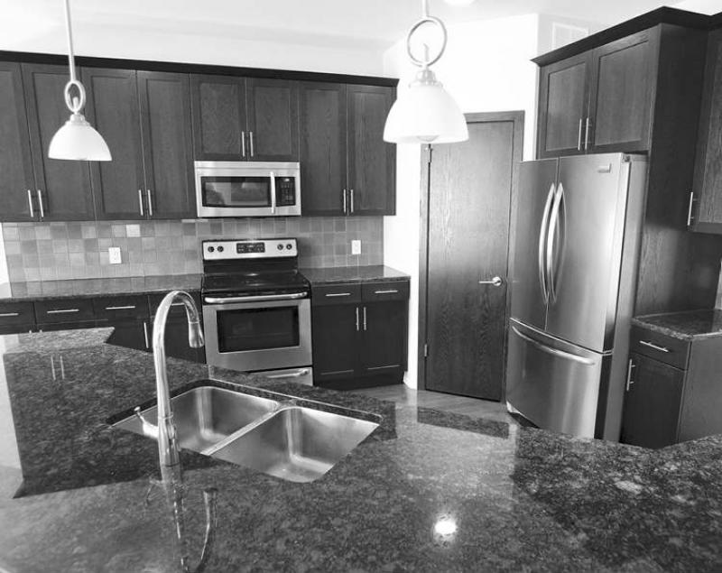 The kitchen features grey granite countertops and dark maple cabinets.