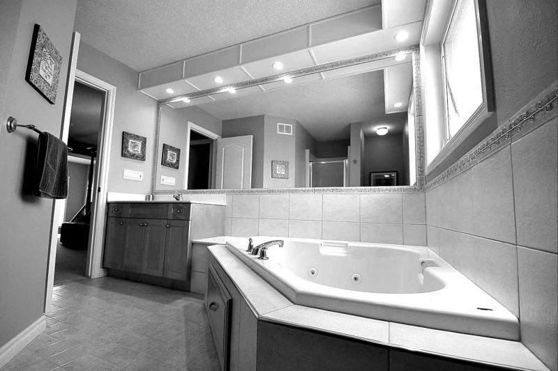 The spa-like ensuite is a bright, elegant space with a large window, tons of rich tile and a corner jetted tub to enjoy a soothing soak in.