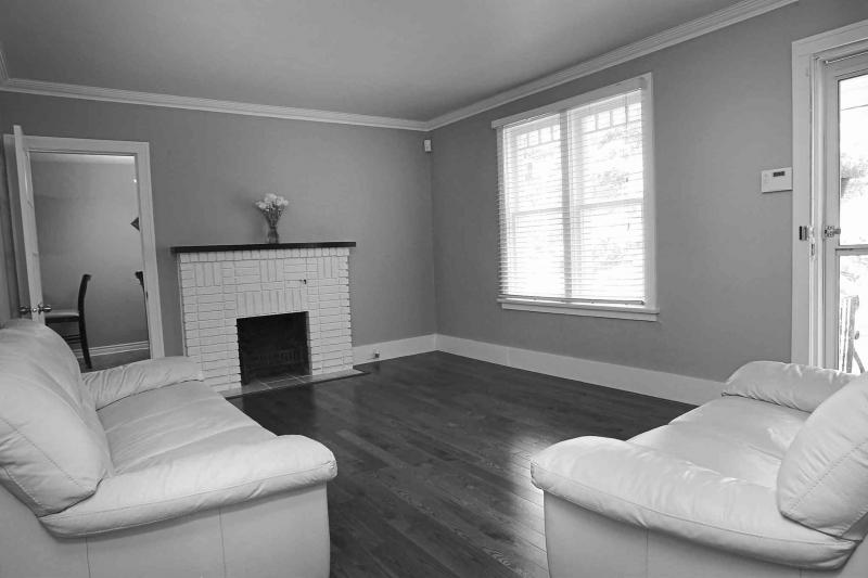 The living room features a wood-burning fireplace with white brick surround, new oak hardwoods and a large window.