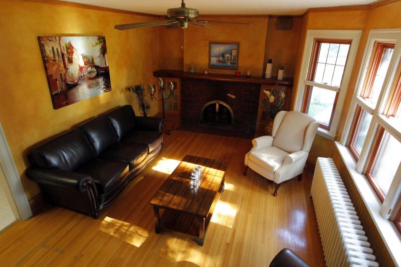 The living room offers a brick fireplace, oak hardwoods and a collection of oversized windows.