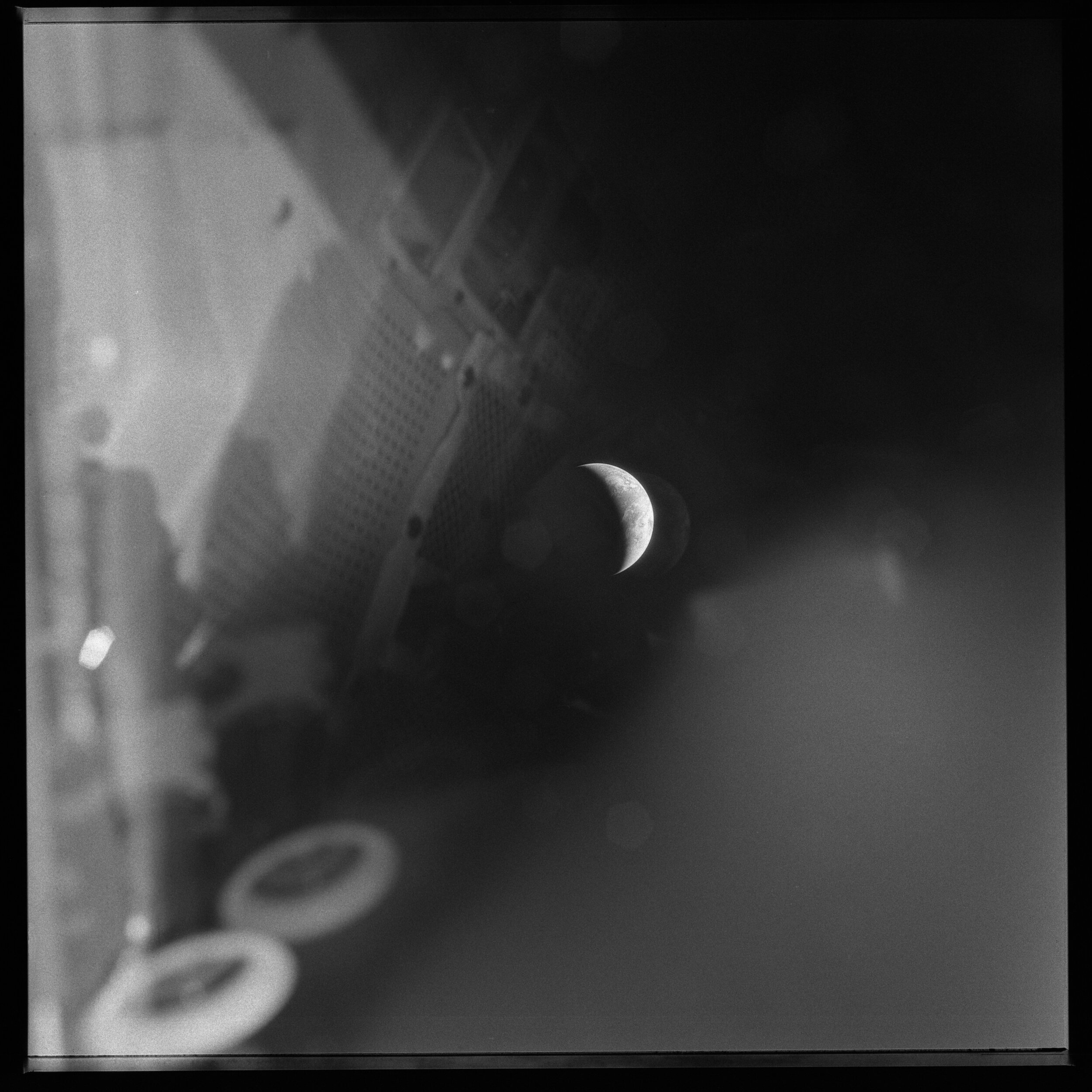  Apollo 13  A crescent Earth, surrounded by reflections of the Lunar Module.  The crew of Apollo 13 were forced to shelter here when the Command Module lost power. This photograph was taken three days after the explosion. By now the crew were severel