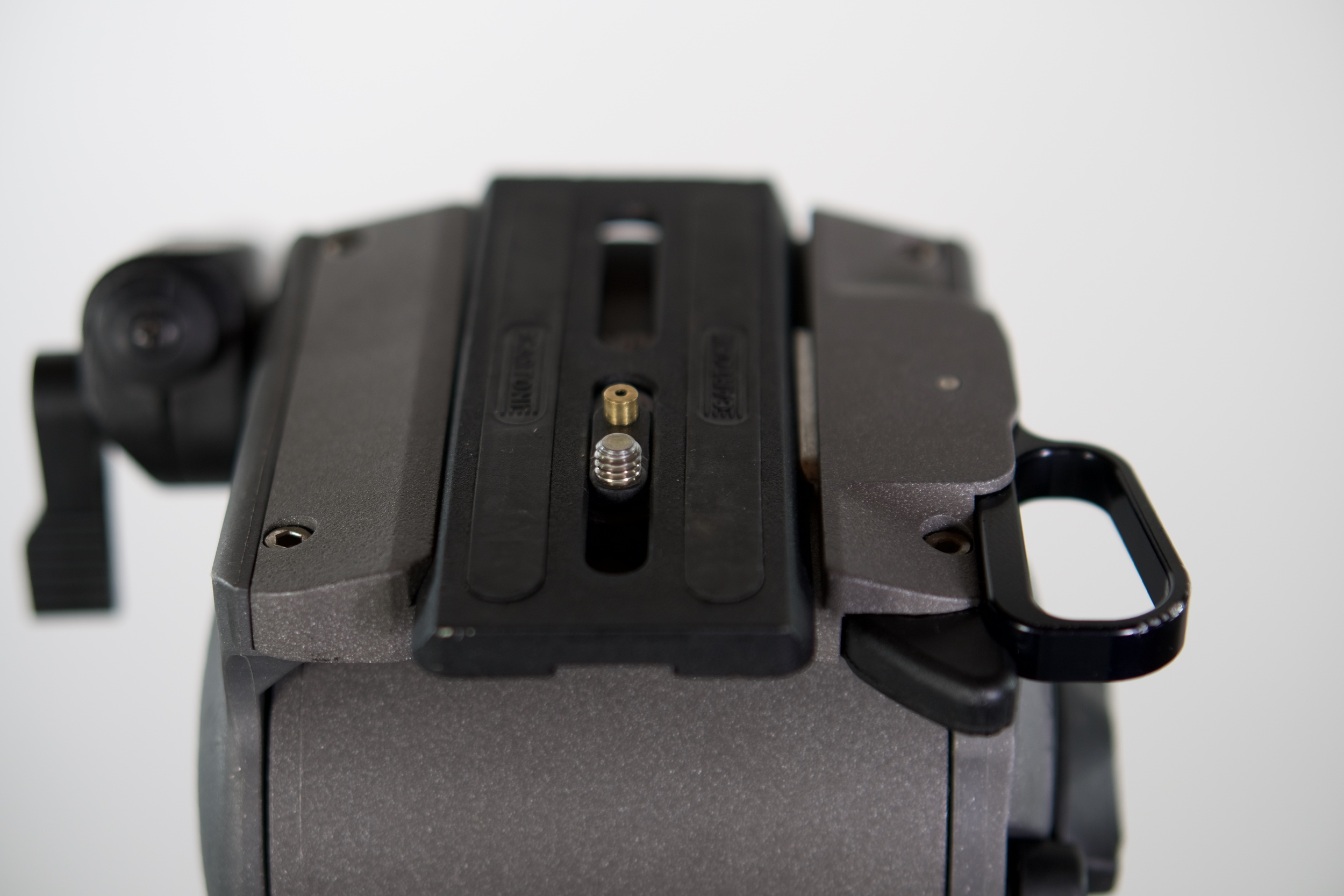 The Cartoni quick-release plate is locked in from the side in a robust but multi-piece base . It uses a threaded screw and a spring-loaded post to prevent twisting. I've always loved the side release - quick, easy, secure, but en toto the Sachtler design is superior.