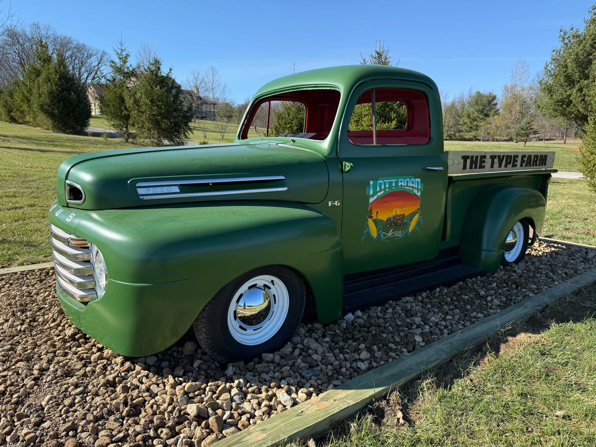 Vintage green Ford truck with colorful illustration on the door reading Lott Road Acres