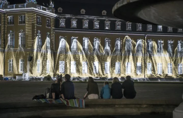 In his projection mapping »CLEANSING«, Israeli artist Eyal Gever floods Karlsruhe's palace virtually and flushes its facade away from its impressively simulated masses of water.