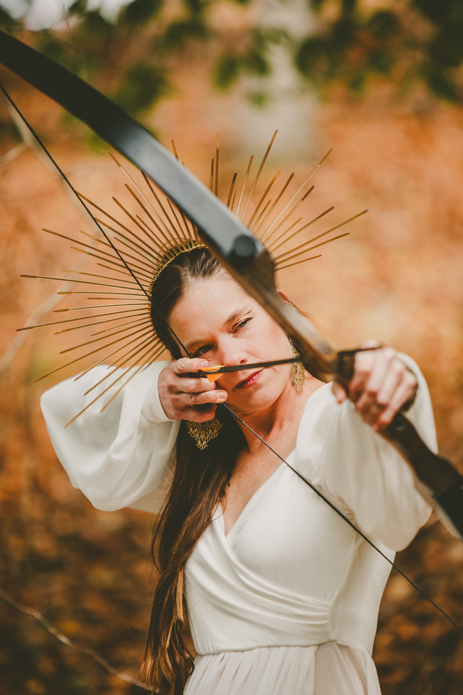 Woman in white dress with a bow and arrow