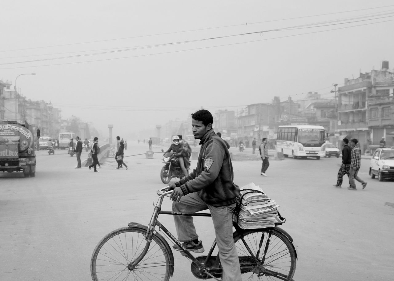 Man on bike with newspapers.