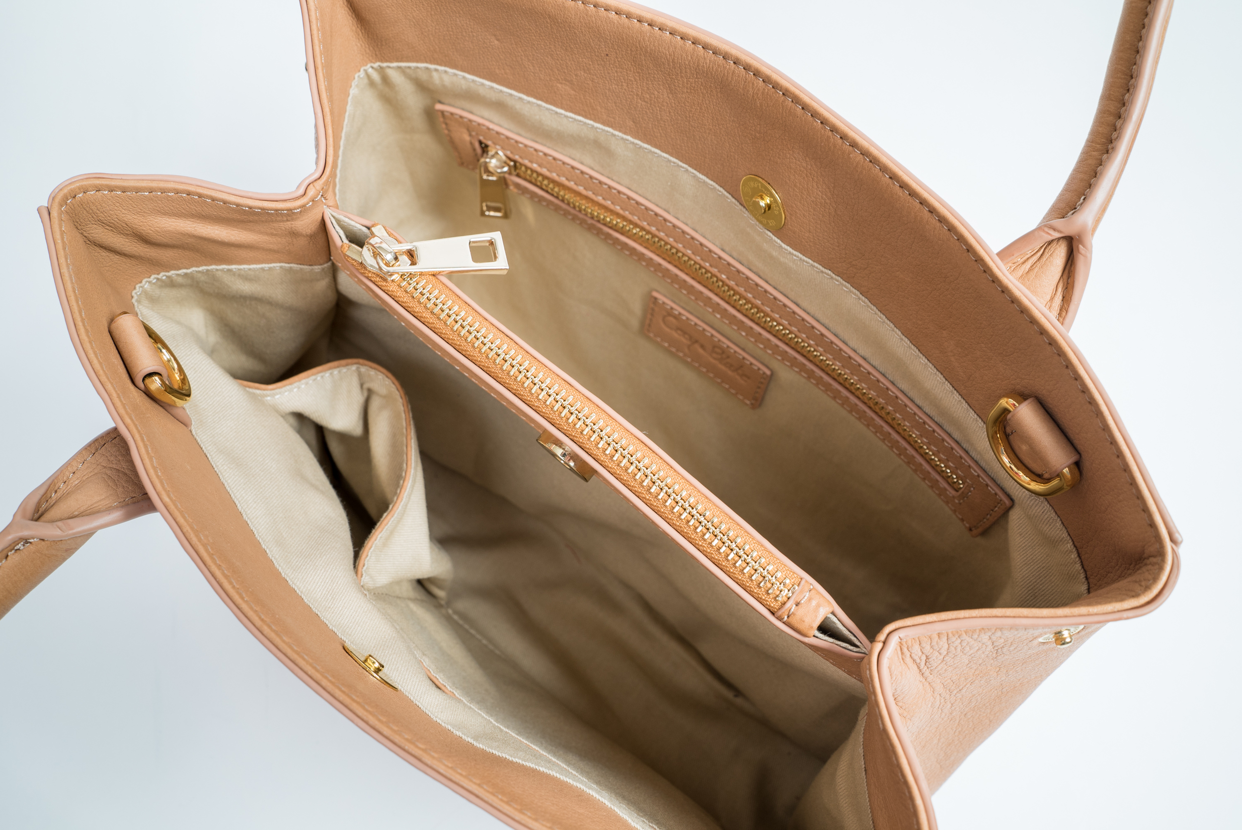Satchel Details: Two snap top closures; Center zip compartment divides interior; Interior: luxurious cotton lining; one zip and two open pockets; Protective feet